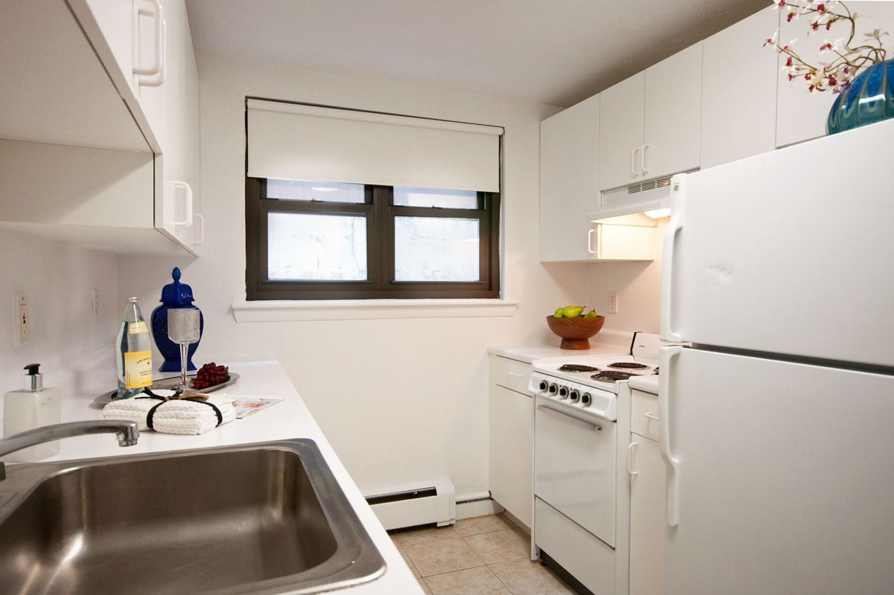 Compact white kitchen with sink, stove, refrigerator, and window