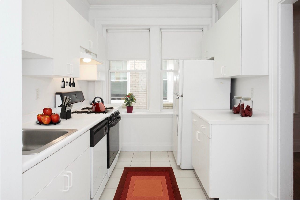 Bright white kitchen with white cabinets, sink, stove, fridge, and a red kettle on the counter.