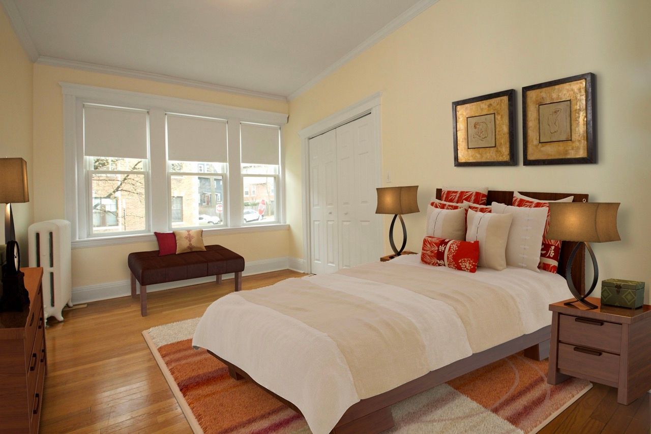 Bedroom with a large bed, two bedside lamps, a windowed wall, and closet doors.