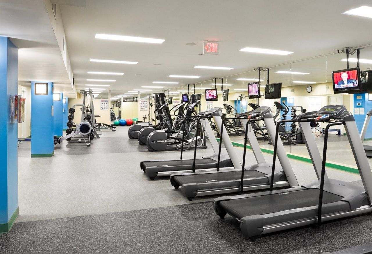 Indoor community gym with treadmills, ellipticals, and free weights.