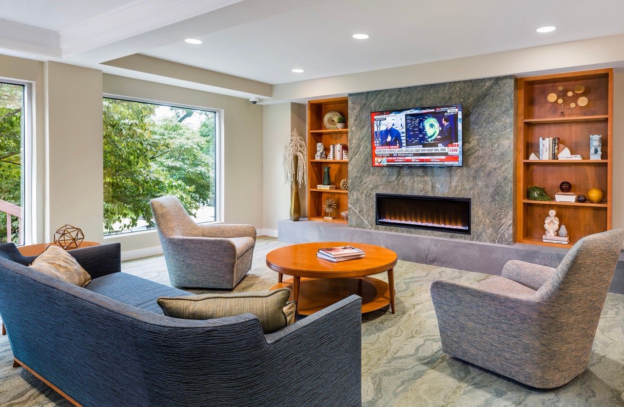 Modern resident lounge with fireplace, large windows, and built-in shelves.