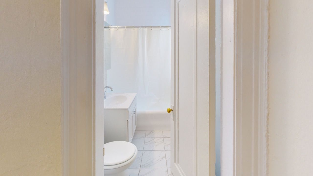 View into a compact apartment bathroom with a sink vanity, toilet, and tub/shower.