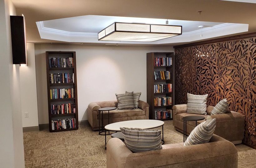 Common lounge area with brown couches, round tables, and bookshelves.