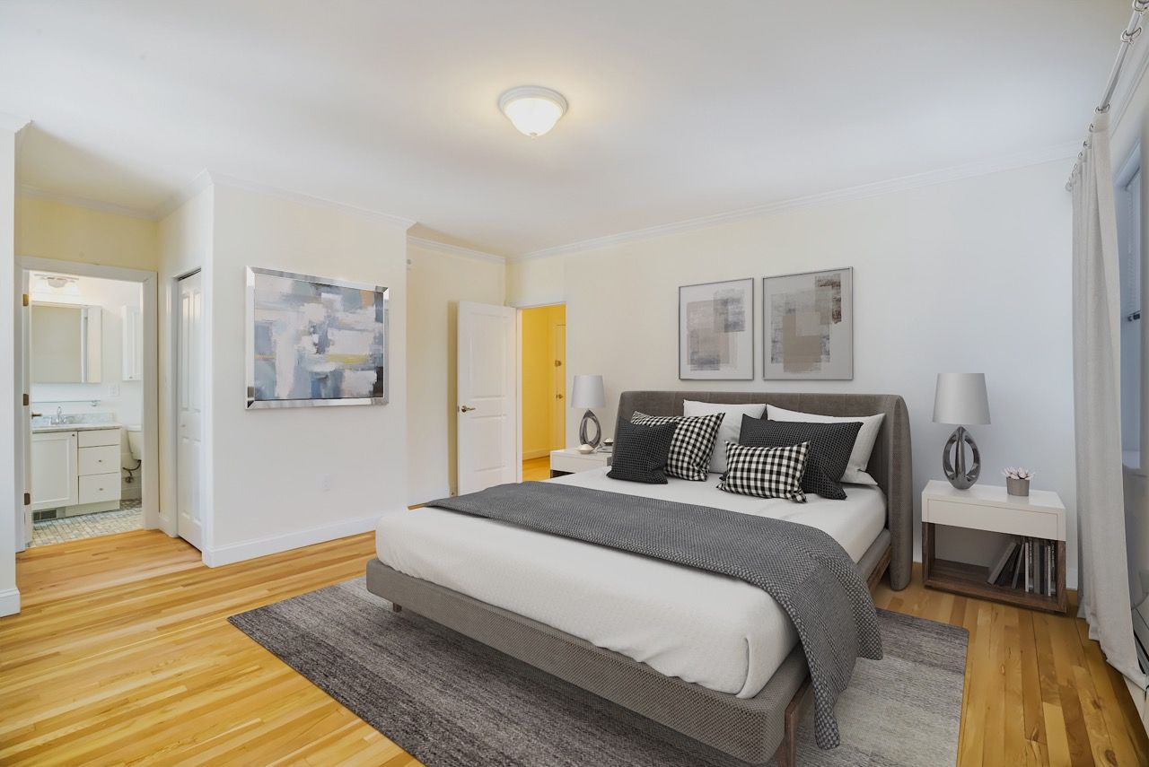 Bedroom in a modern apartment with a large bed, two nightstands, and hardwood floors.