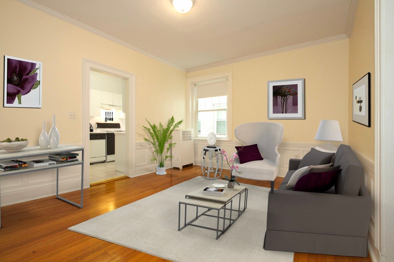 Living room in an apartment: beige walls, wood floors, gray sofa, white chair, and coffee table.