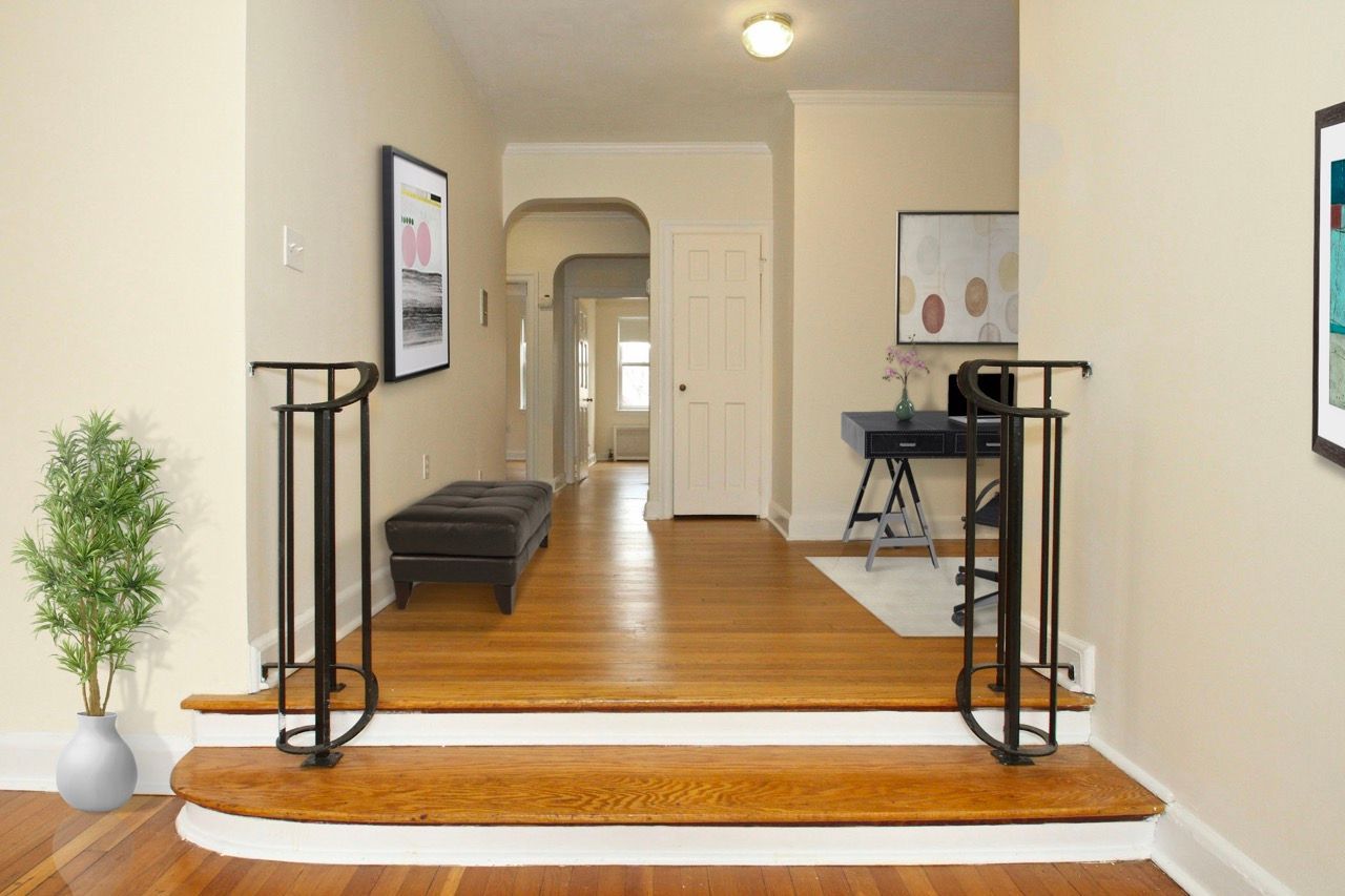 Interior apartment entry hall with wooden floors, curved steps, and a desk.