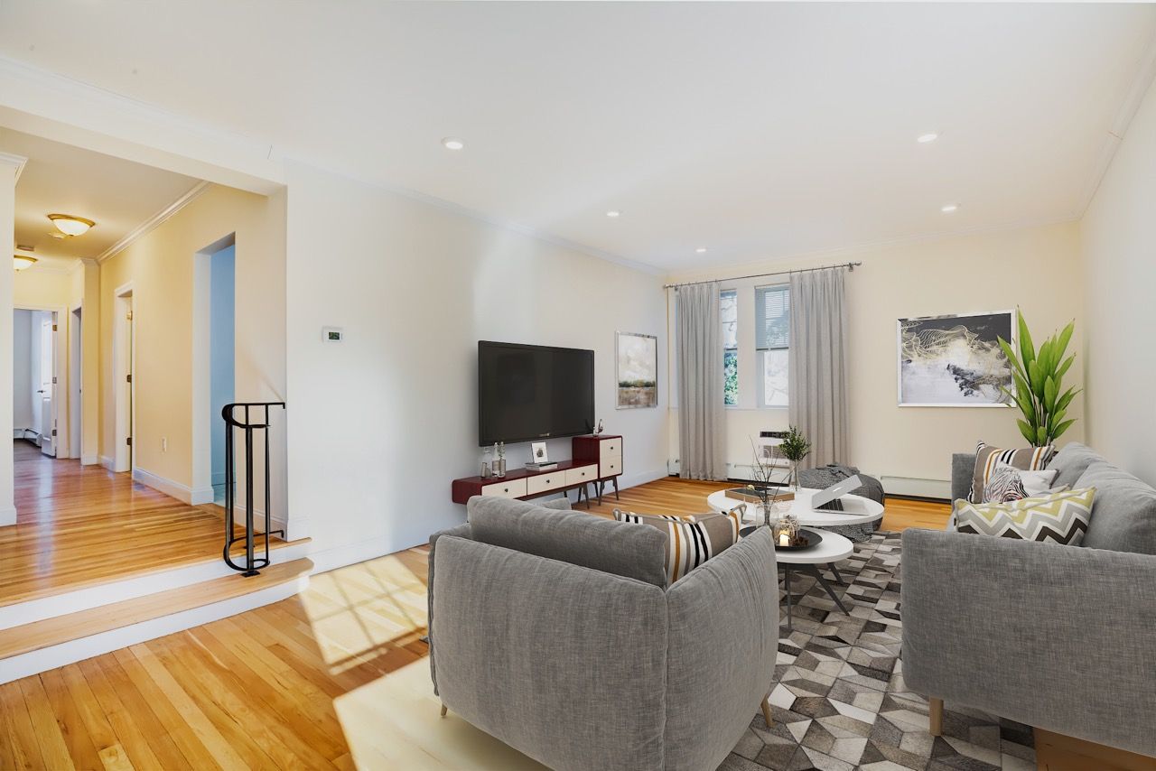Bright living room with gray sofas, a coffee table, rug, and wall-mounted TV.
