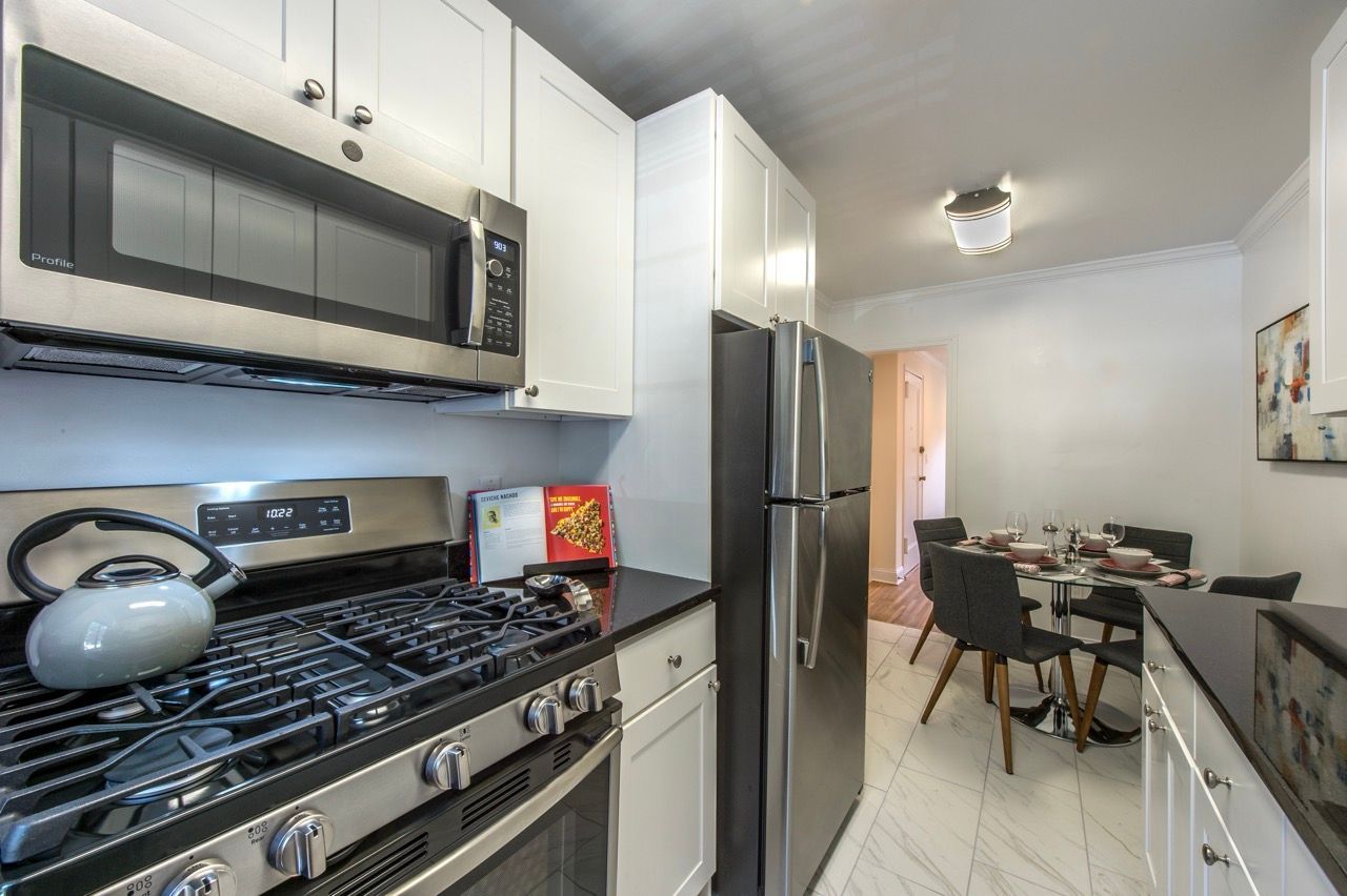 Modern kitchen with stainless steel appliances, white cabinets, and a dining area.