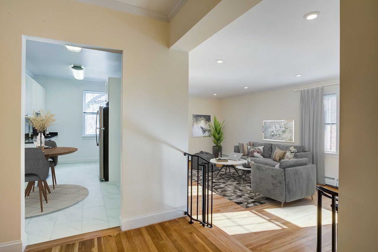Open living room with a gray sofa, coffee table, rug, and a view of the kitchen/dining area.