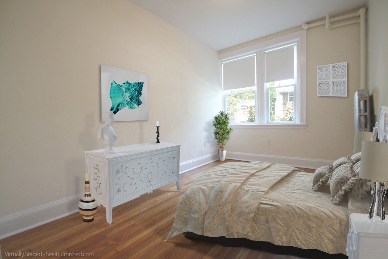 Bright bedroom with a queen bed, white dresser, and large front window.
