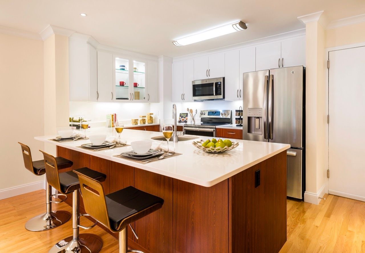Modern apartment kitchen with white cabinets, stainless appliances and a large island.