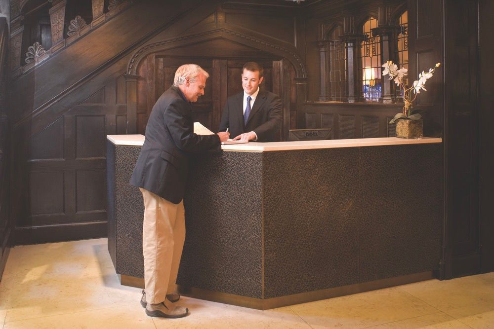 Two men at a front desk in a dark wood lobby.