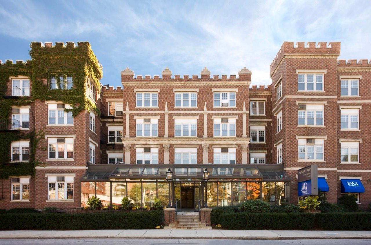 Brick apartment building with ivy on the left and a glass-enclosed entrance.