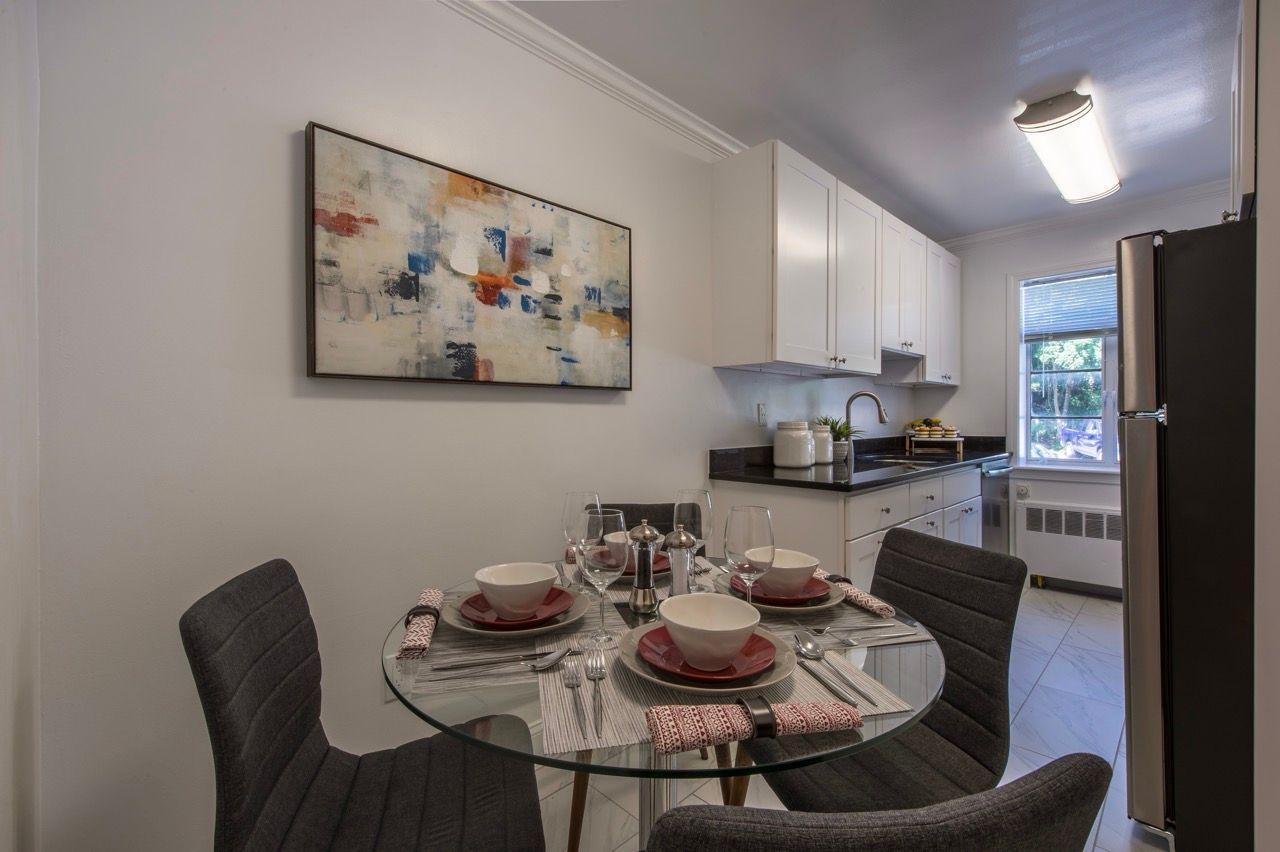 Round glass dining table with place settings in a white kitchen of an apartment.