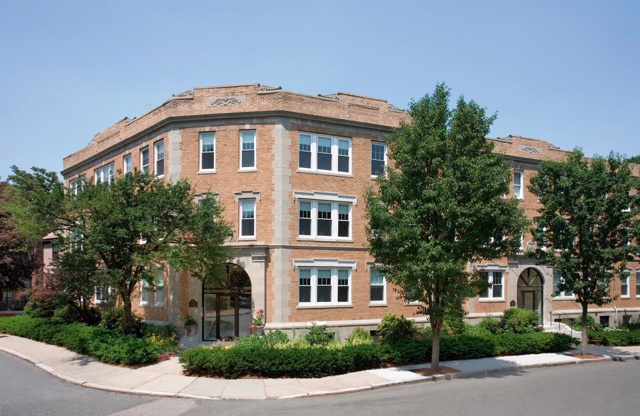 Brick apartment building exterior with arched entrances and landscaping.