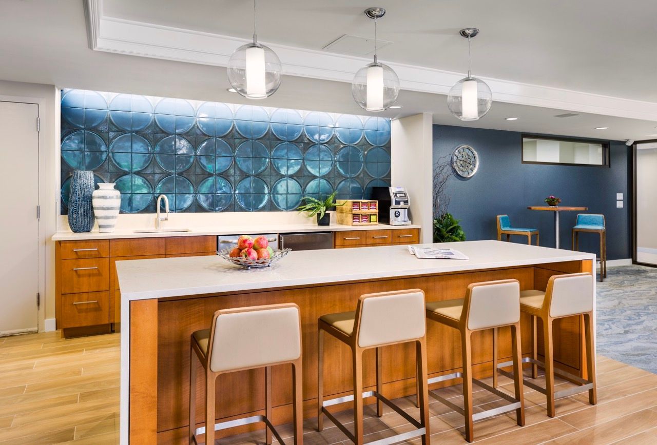 Modern communal kitchen with island, seating, and coffee station.