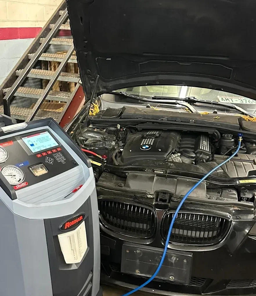 Car in garage with hood open, connected to a diagnostic machine by a blue cable | Albeik Auto Service