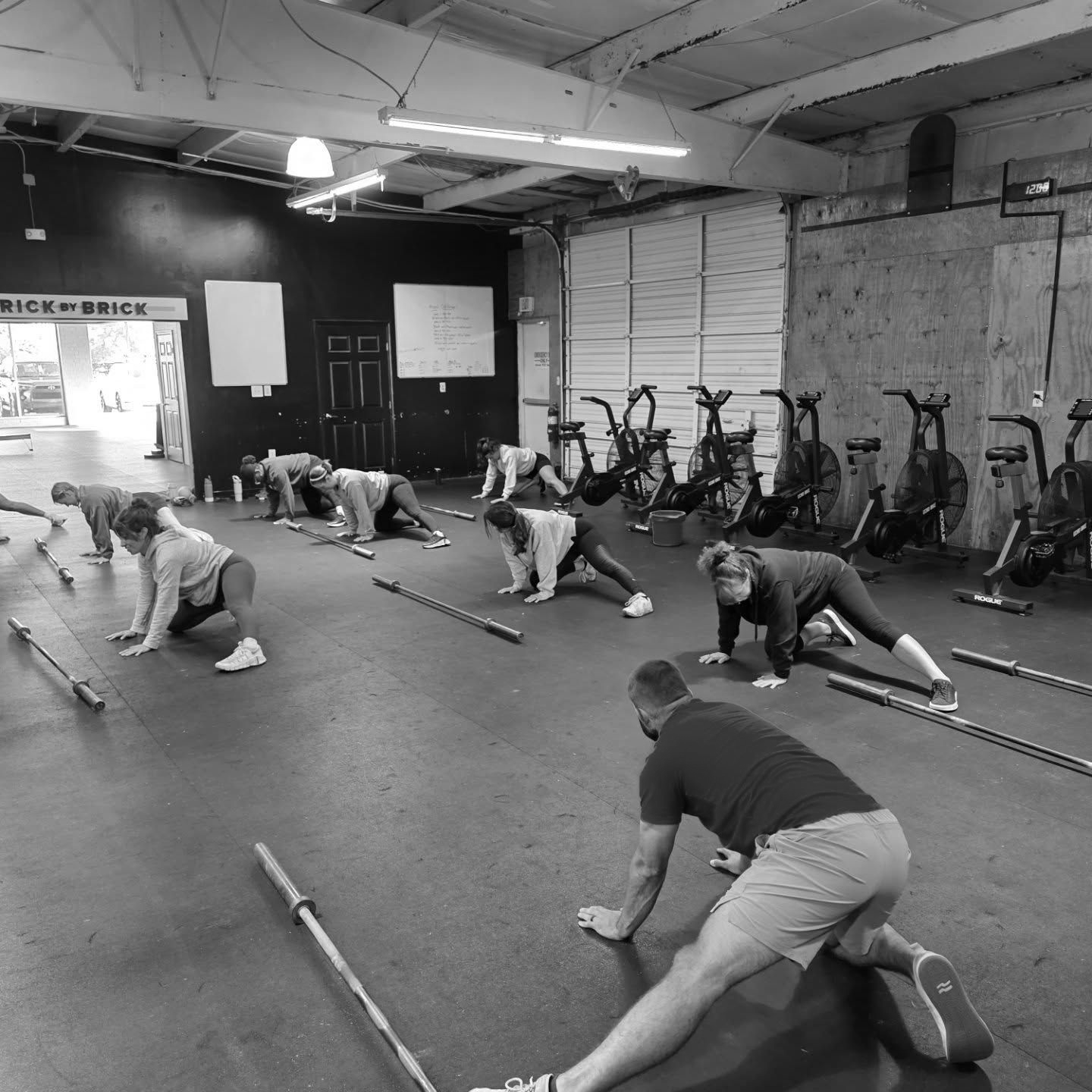 People stretching on CrossFit Bohica in Goldsboro, NC floor during a group workout class, black-and-white photo.