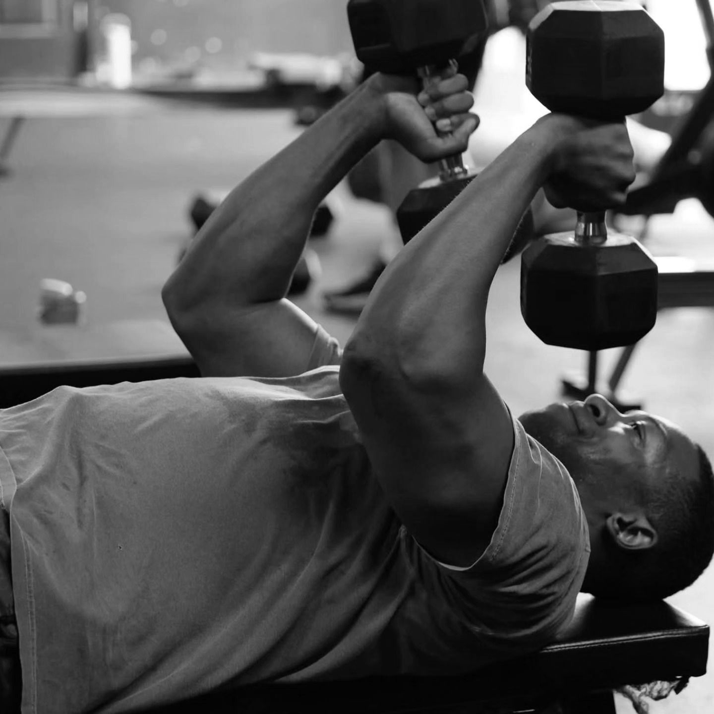 Man lifting dumbbells on a gym bench in CrossFit Bohica in Goldsboro, NC black and white