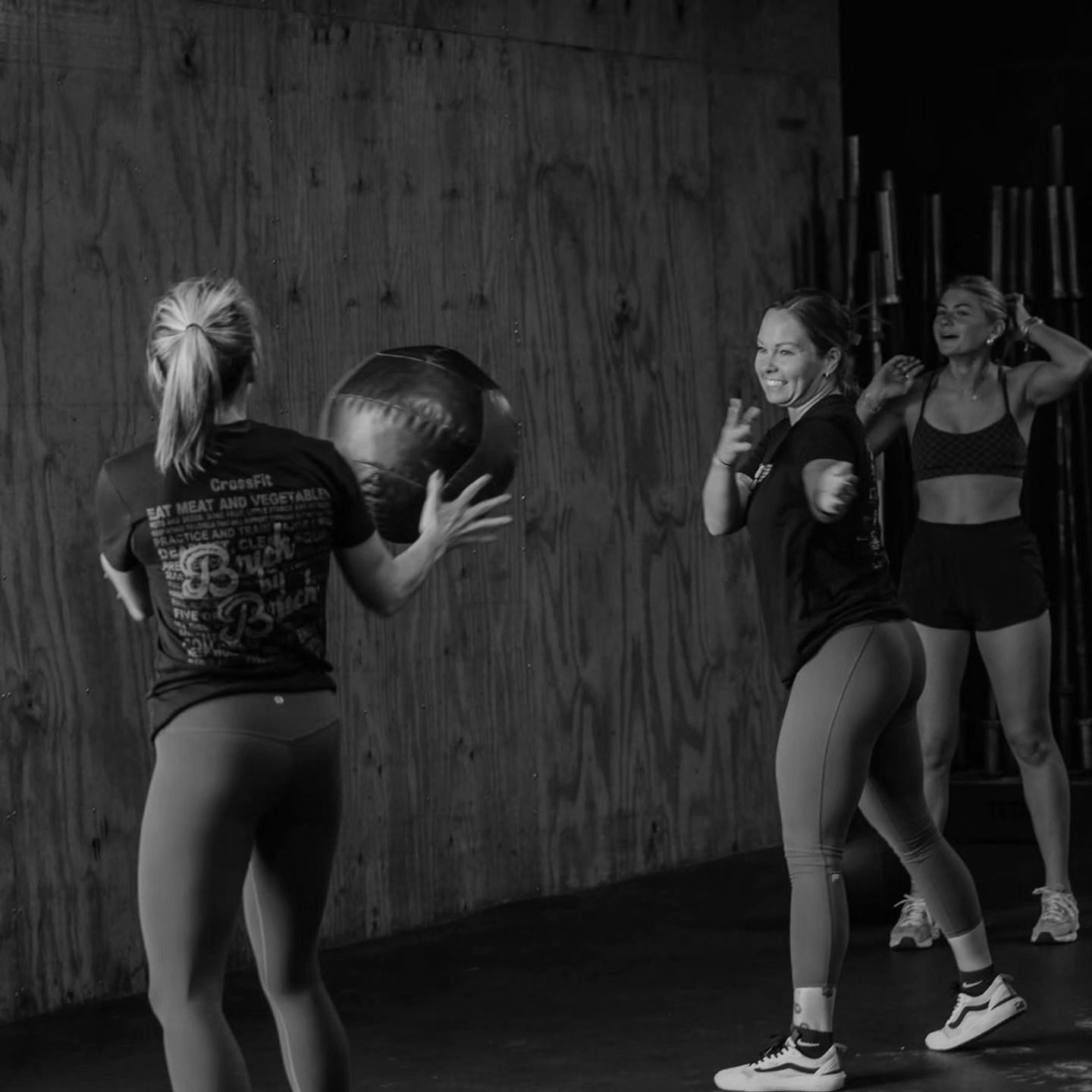 Women exercising with medicine balls in CrossFit Bohica in Goldsboro, NC, one facing a wall while two others stand nearby.