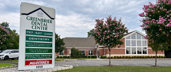 Greenfield Dental Center sign in front of a brick building with trees and pink blossoms