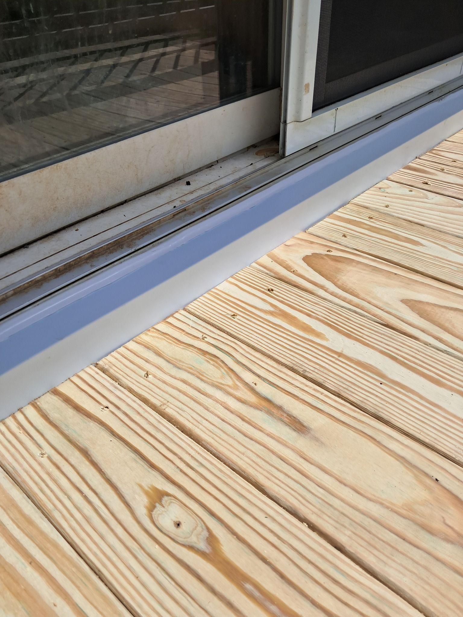 Sliding glass door with a blue strip at the base, adjacent to wooden deck.