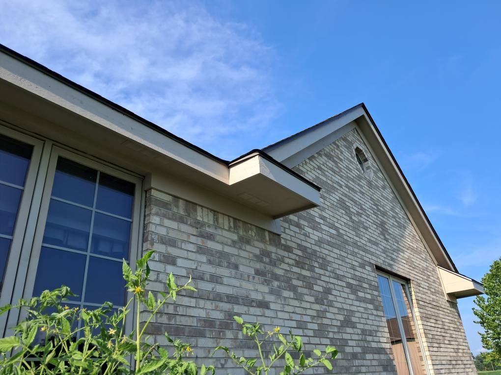 Brick building with dark roof, window and blue sky. Brick building with dark roof, window and blue sky.