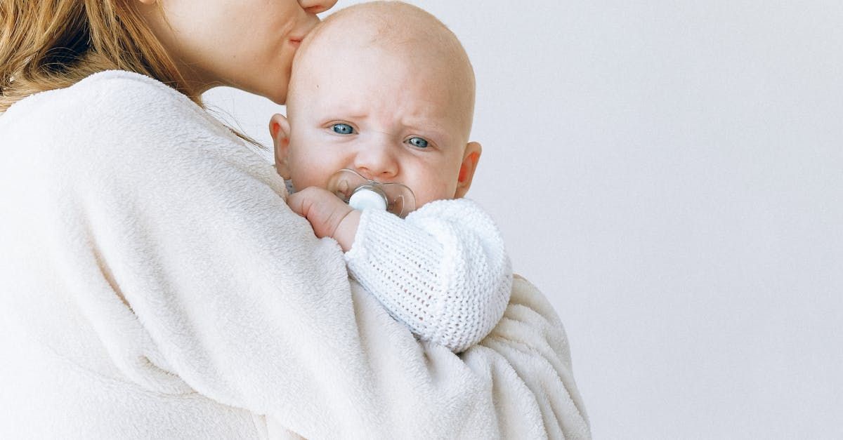 A woman is holding a baby in her arms and kissing it on the cheek.