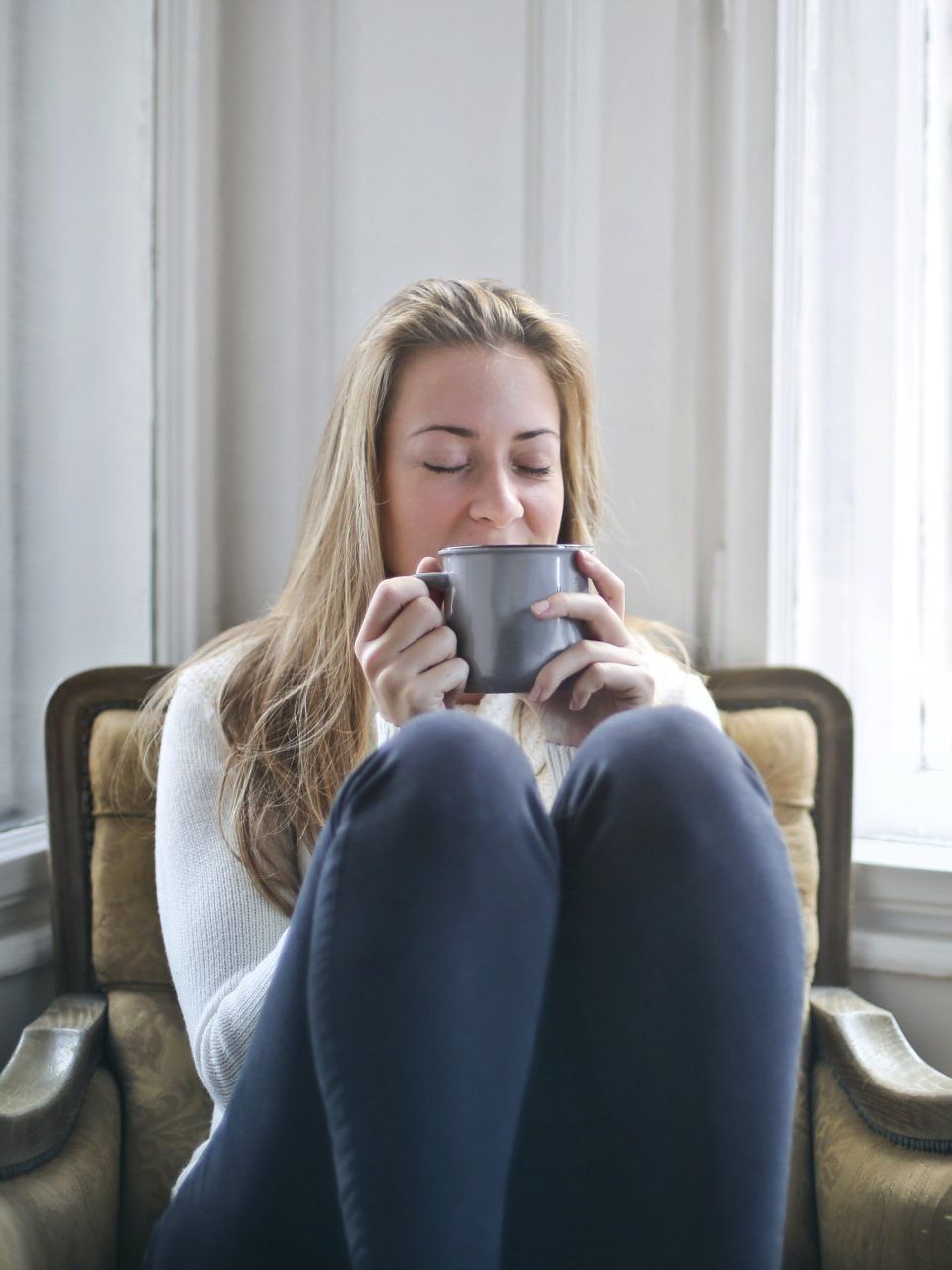 a woman is sitting in a chair drinking a cup of coffee seeking help with depression