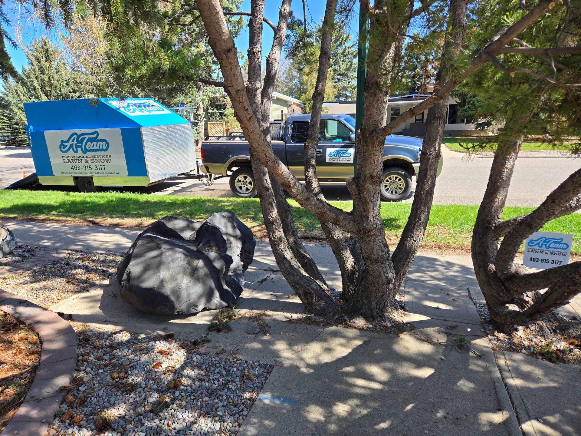 Blue-and-white shelter outdoors near a parked SUV, with rocks, trees, and a concrete walkway in the foreground