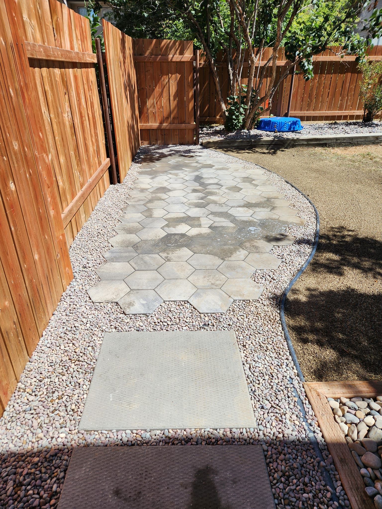 Large square pavers and light-colored hexagonal tiles surrounded by decorative gravel.