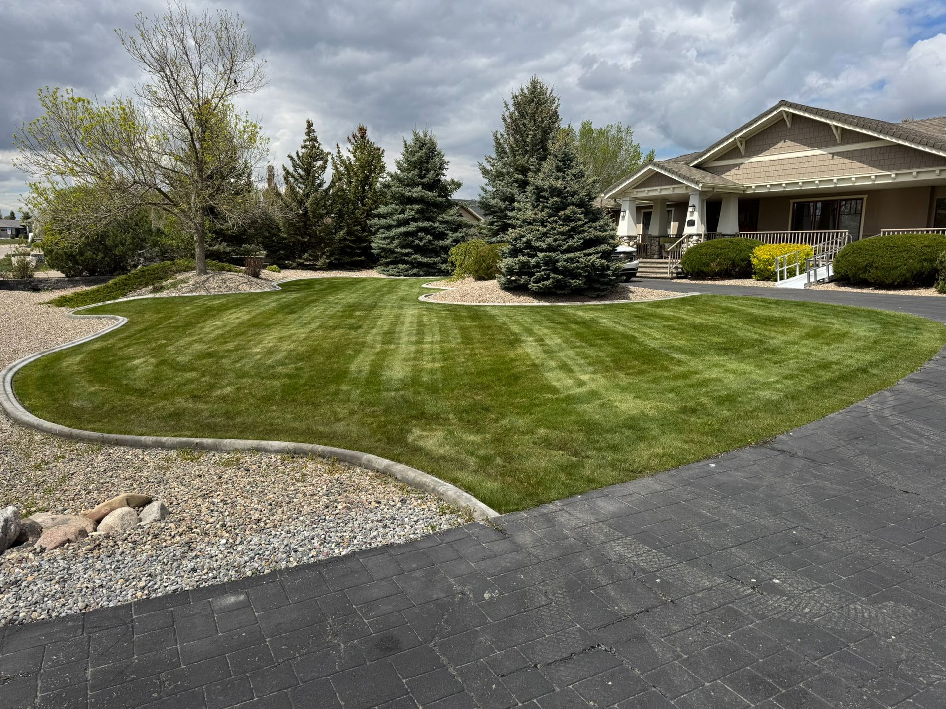 Suburban house with landscaped lawn, curved driveway, and cloudy sky