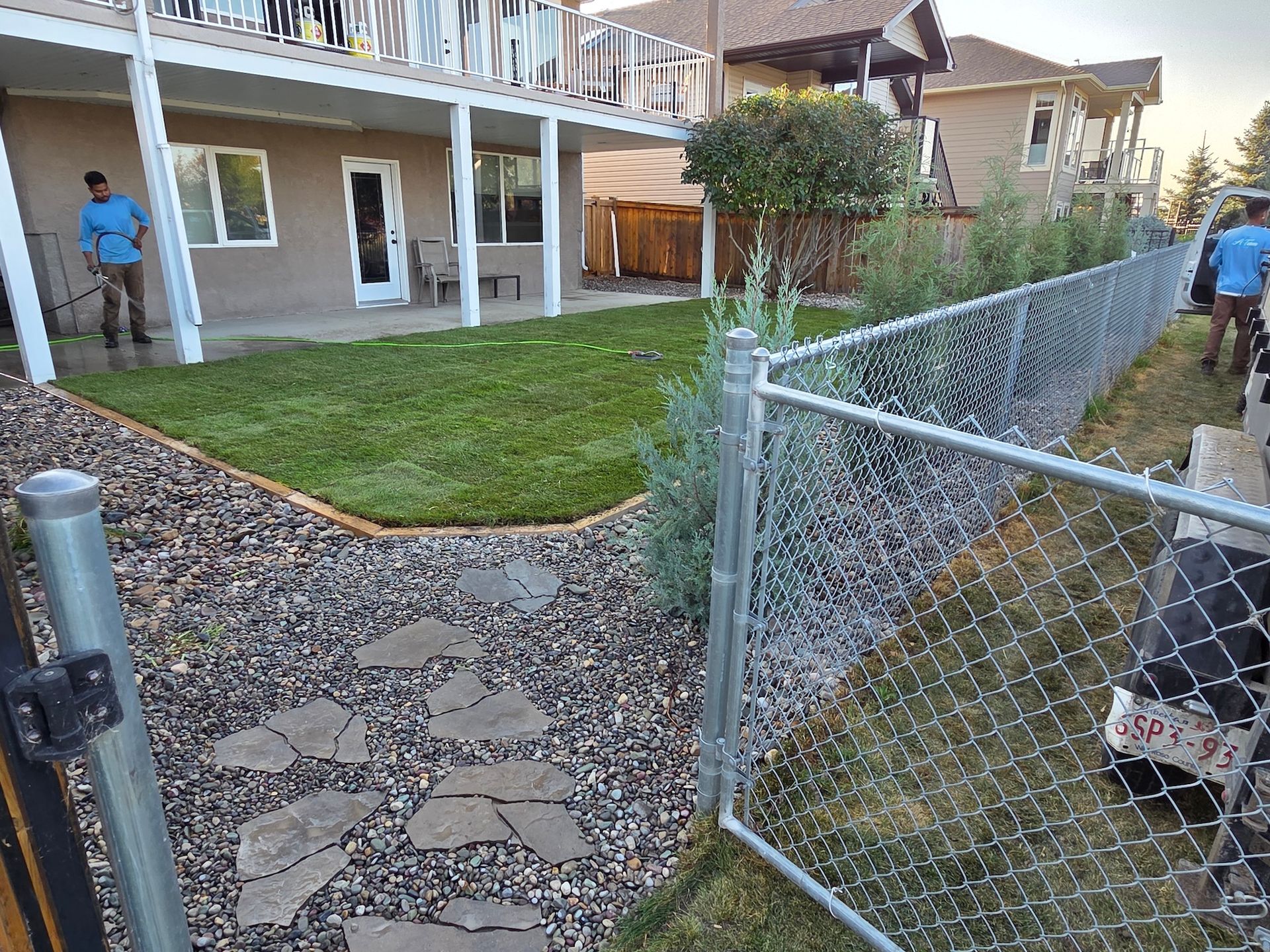 A landscaped backyard with a stone path, grass lawn