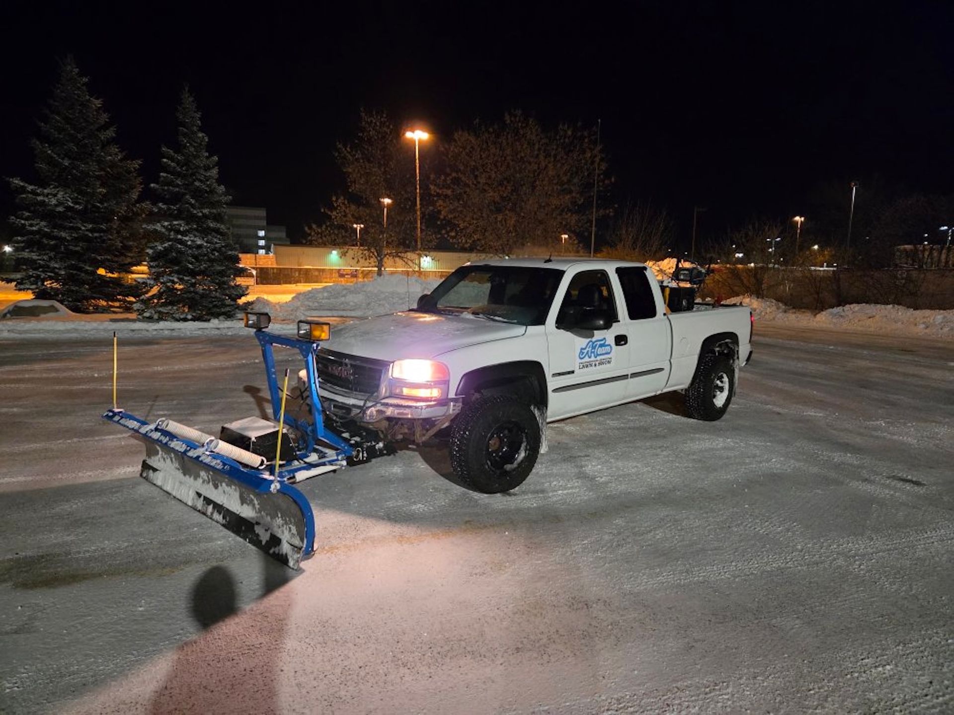 A white pickup truck with a blue snow plow.