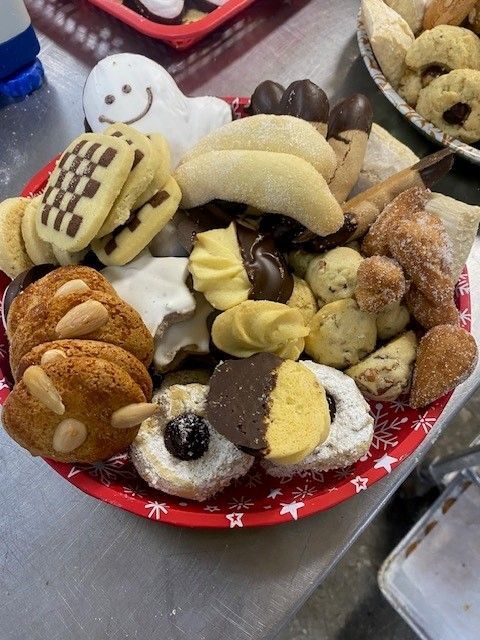 A red plate overflowing with various Christmas cookies, including some dipped in chocolate and dusted with sugar.