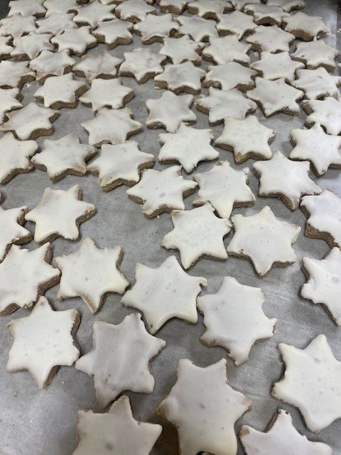 Star-shaped cookies, iced with white glaze, arranged on a baking sheet.