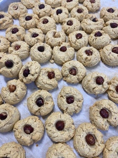 Cookies on parchment paper, each with a hazelnut center.