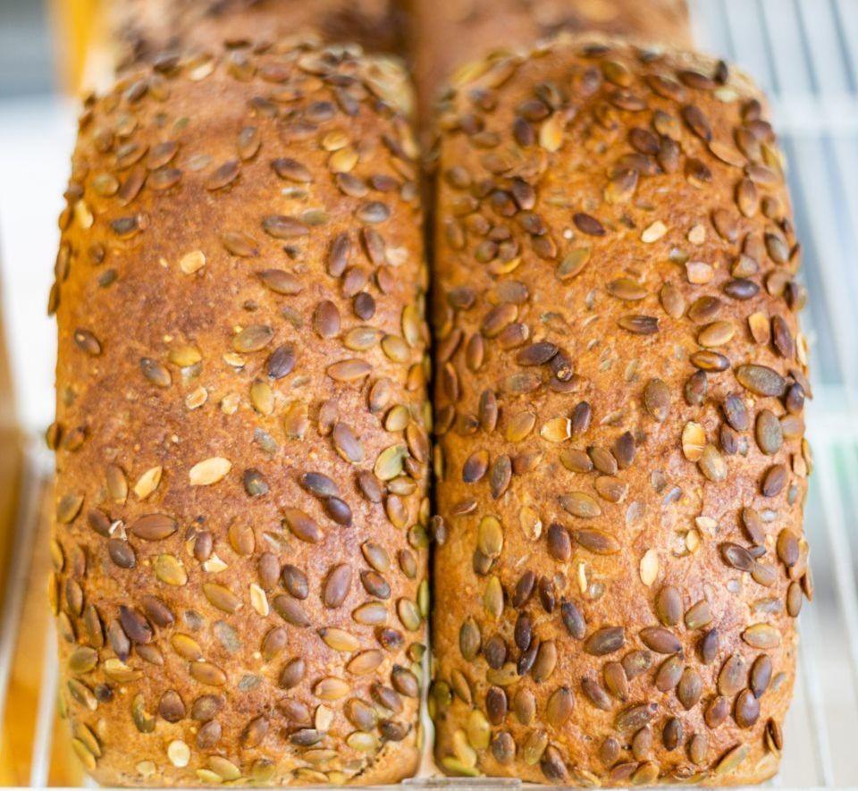 Two loaves of pumpkin seed bread on a shelf, close-up.
