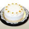 White frosted cake with orange toppings on a black plate with a white lace doily.