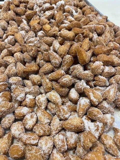 Tray of golden fried dough pieces coated in white sugar.