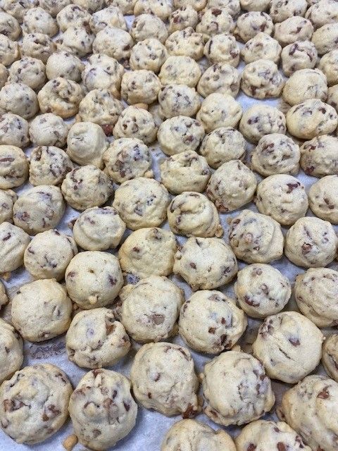 Raw cookie dough balls with chocolate chips arranged on a baking sheet.