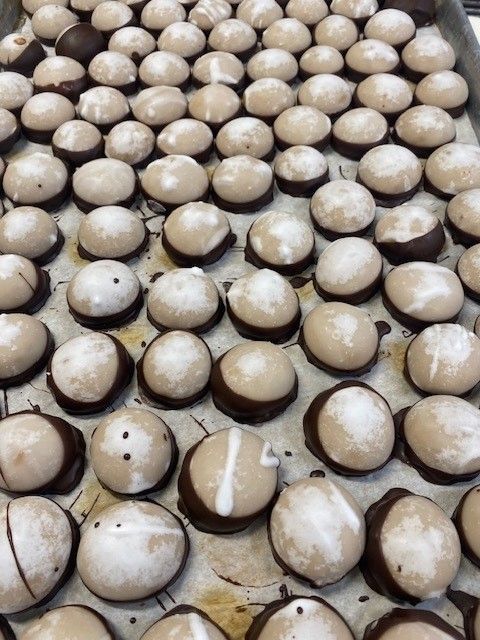 Tray of white-topped, chocolate-bottomed candies, some with sugar dusting.