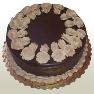 Chocolate cake with chocolate frosting and cream-colored buttercream decorations on a gold cake base.