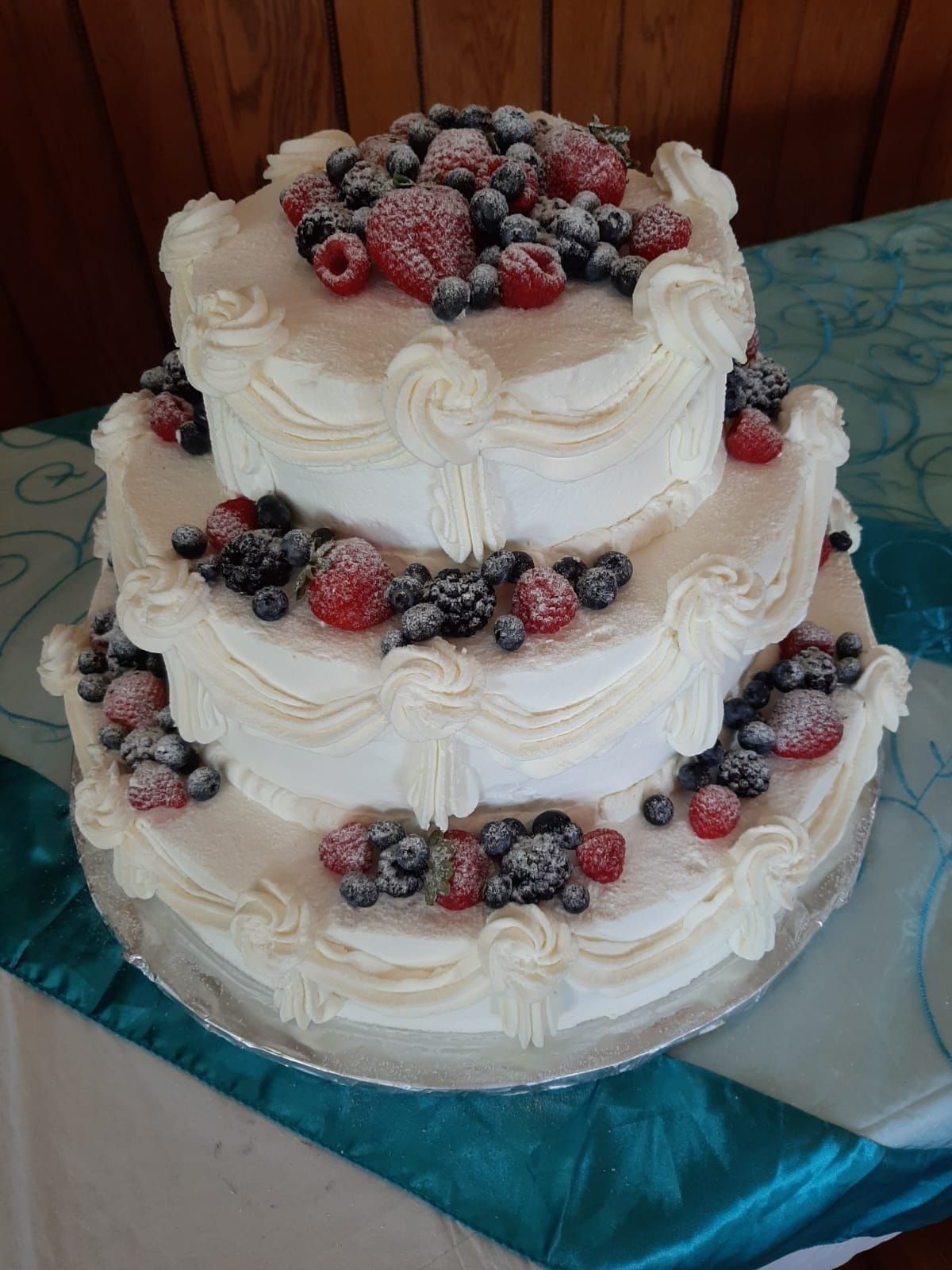 Three-tiered white cake with piped frosting and sugared berries.