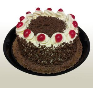 Black Forest cake on a black plate, with whipped cream, cherries, and chocolate shavings.