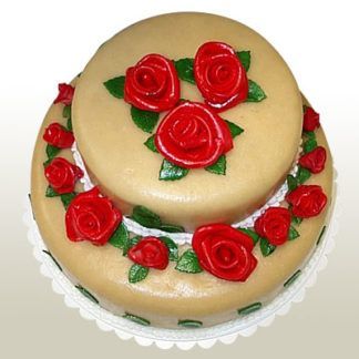 Two-tiered cake with red rose decorations and green leaves, on a white doily.