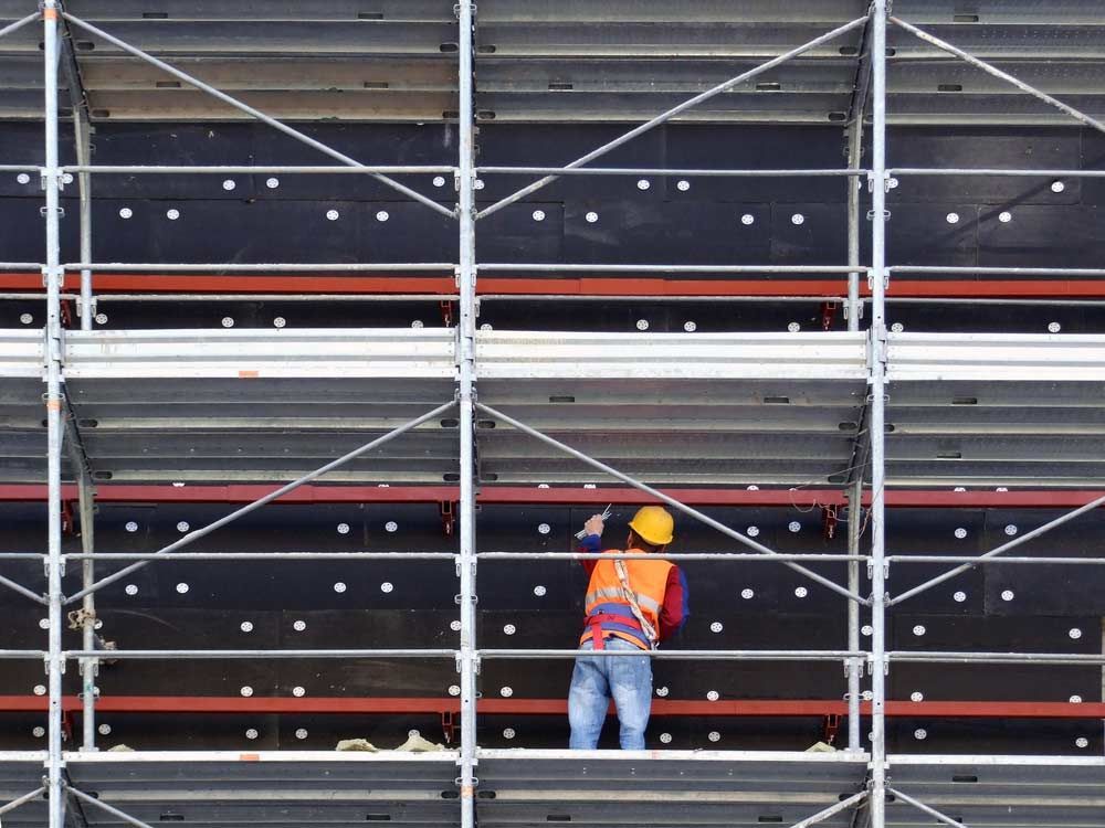 A Construction Worker Is Standing On Top Of A Scaffolding — Triple S Scaffolding In South West Rocks, NSW