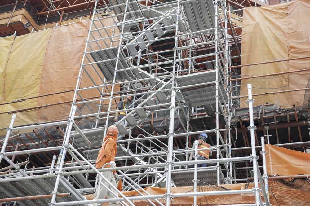 A Group Of Construction Workers Are Standing On Scaffolding On Top Of A Building — Triple S Scaffolding In Port Macquarie, NSW
