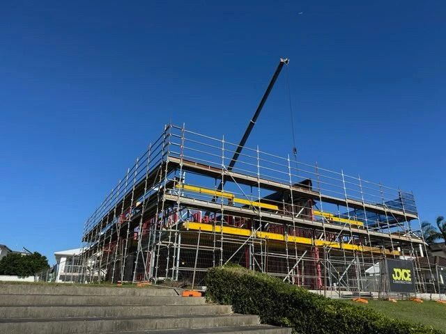A Large Building Is Being Built With Scaffolding Against A Sunset Sky — Triple S Scaffolding In Port Macquarie, NSW