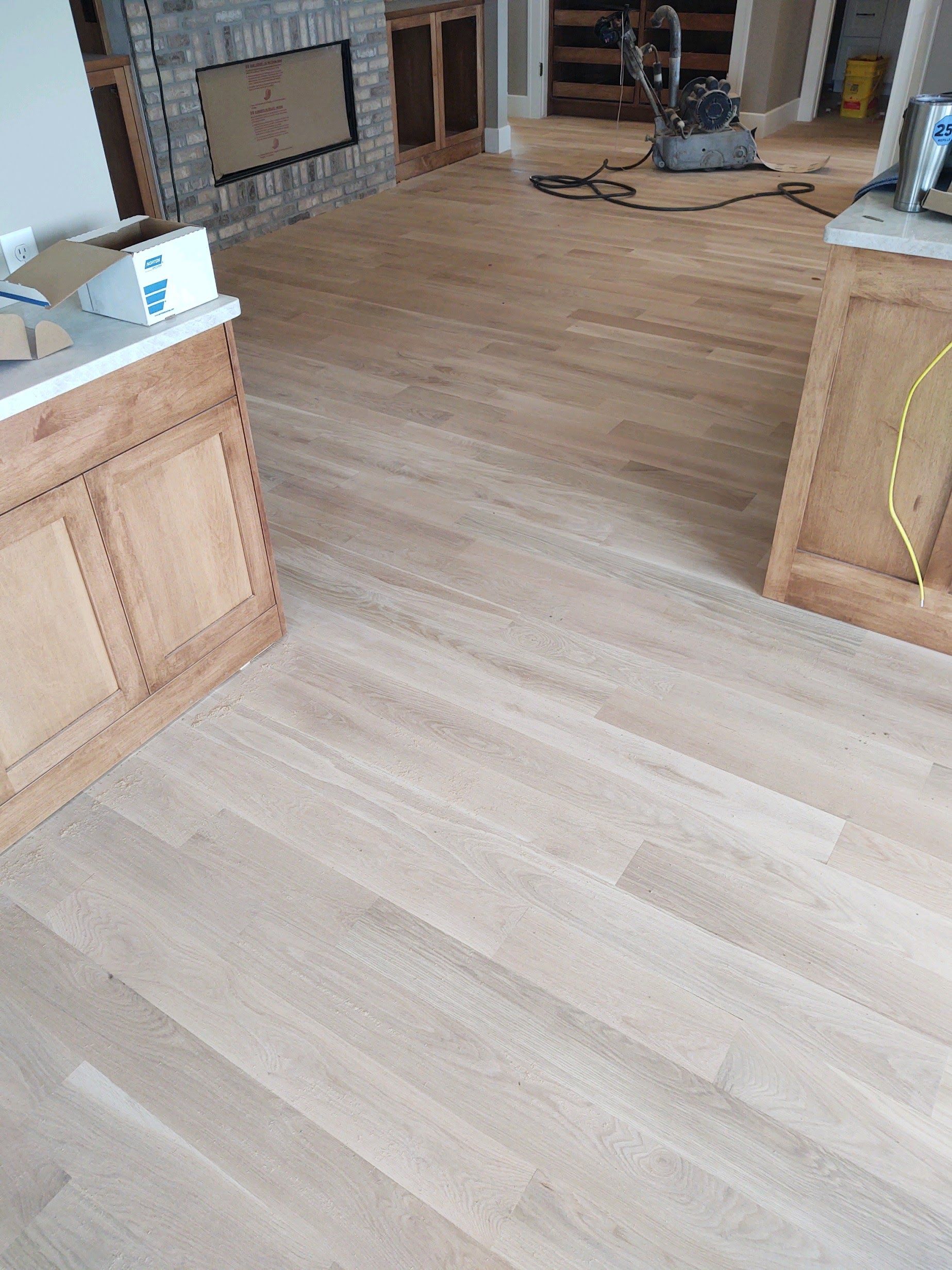 Empty living room with light wood flooring and a fireplace in the background